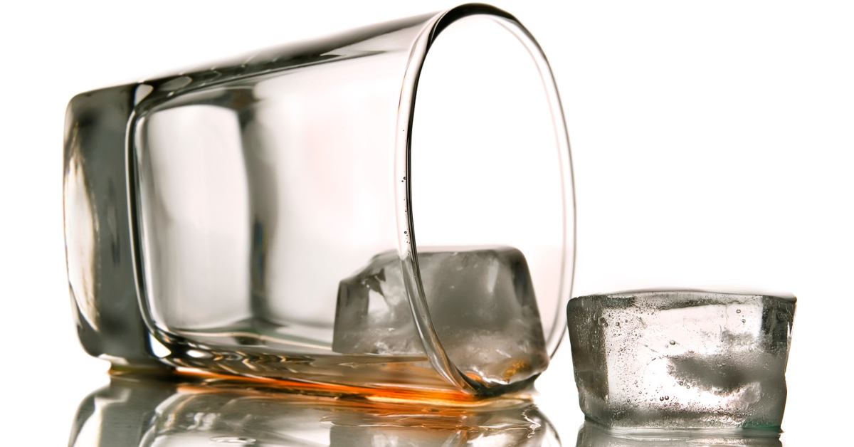 A spilled glass of alcohol with melting ice cubes